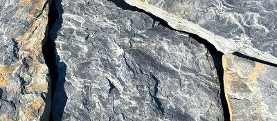 Фото плоского, волнистого камня серо-синего цвета.